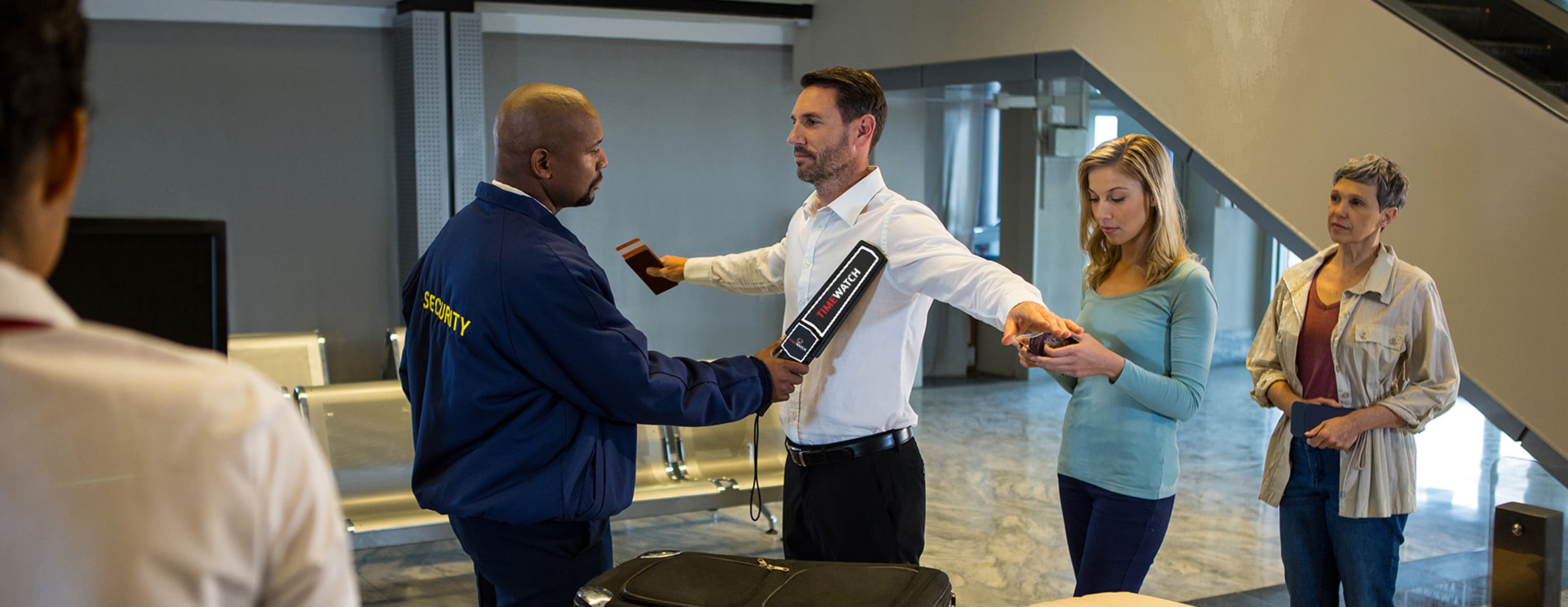Security officer screening a person with the TW-HH100 hand held metal detector