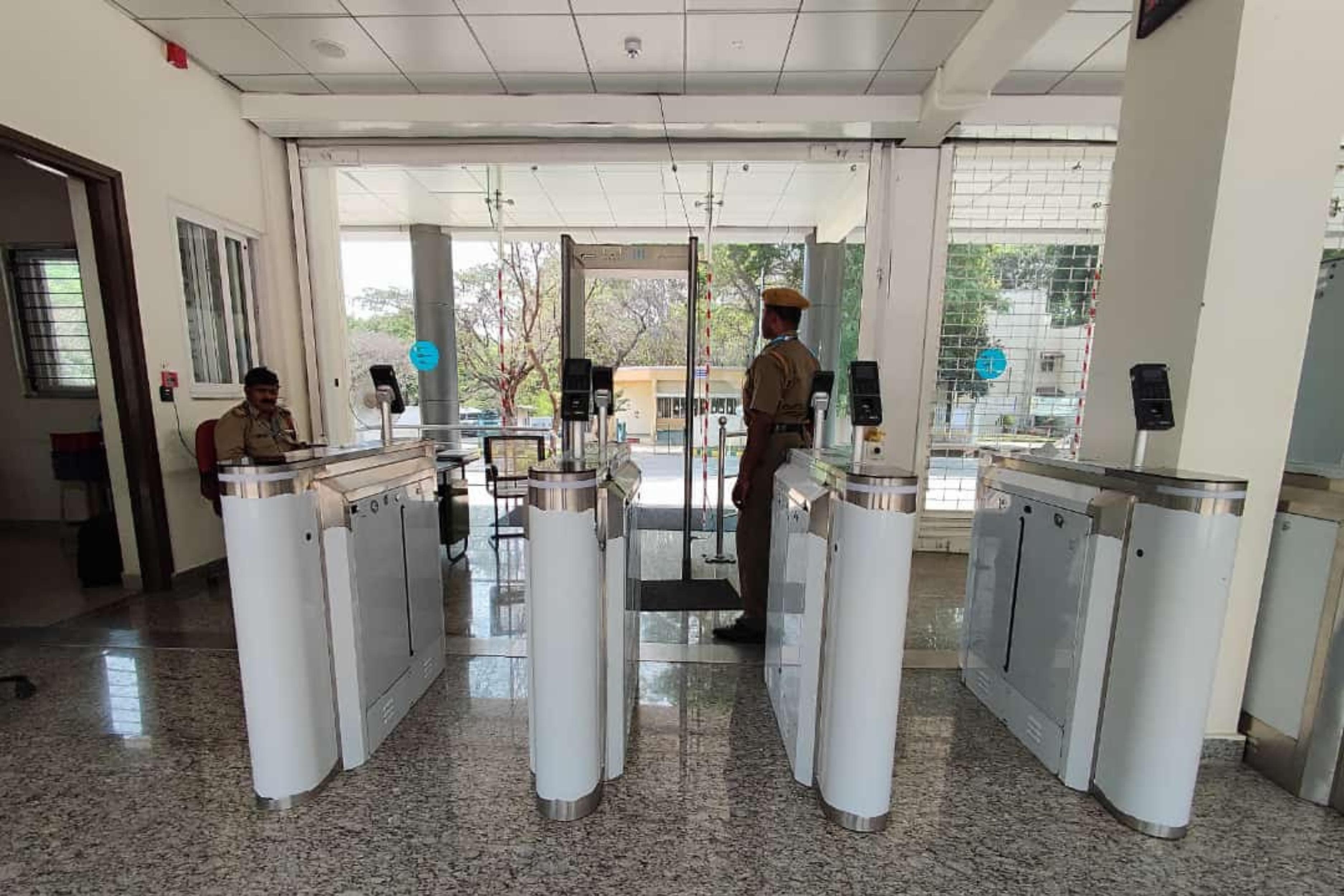 Swing barrier lanes in an office lobby in Saudi Arabia with a glass panel swinging open as a visitor approaches